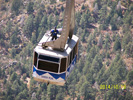 View of tram car coming in to upper terminal. Note the worker casually standing on the top!